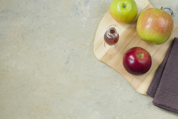 Homemade vinegar made from ripe apples on a wooden board. Light background top view copy space.