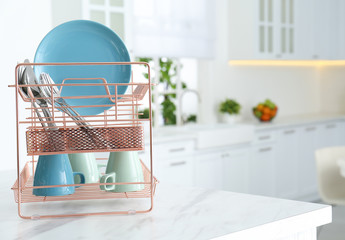 Clean dishes on drying rack in modern kitchen interior, space for text