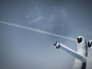 Cropped Image Of Woman Holding Cigarette Against Sky