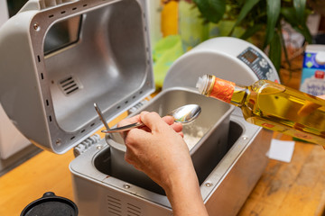 A woman's hand is working on a bread maker.