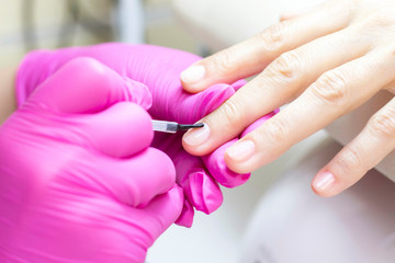 Obraz na płótnie Canvas shellac. man in pink gloves puts nail polish on a girl.