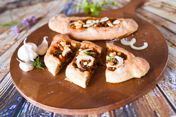 würzige türkische pide mit Fetakäse Zwiebeln Knoblauch auf einem Schneidebrett aus Holz 