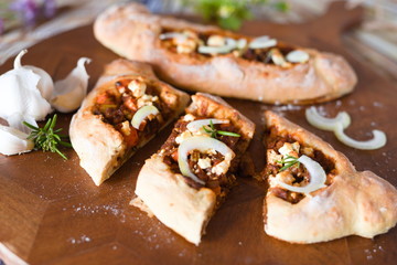 würzige türkische pide mit Fetakäse Zwiebeln Knoblauch auf einem Schneidebrett aus Holz 