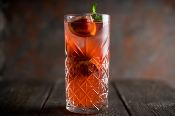 Red cocktail with blood oranges and thyme on the rustic background. Selective focus. Shallow depth...