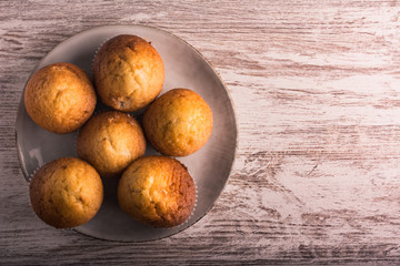 Six delicious freshly made muffins on a plate. Wood background. Horizontal format.