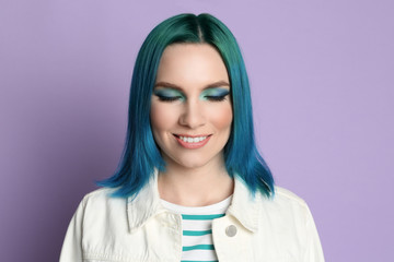 Young woman with bright dyed hair on lilac background