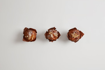 Small tasty sweet muffins sprinkled with powdered sugar isolated on white background. Dessert to drink tea with. Gourmet confectionery products baked by confectioner. Junk food and nutrition concept