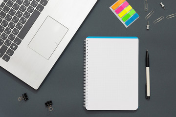
Workplace in the office. Gray table. The photo shows a laptop, colorful stickers, pencils, office accessories. Office background.