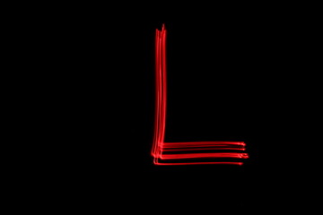Long exposure photograph of the letter l in neon red colour fairy lights against a black background. Light painting photography. Part of an alphabet series. 