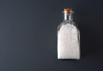 Salt background with glass bottle full of sea salt.