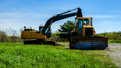 Excavator and bulldozer in a field next to a gravel road