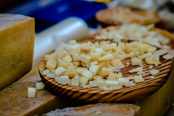 Cheese slices on a wooden plate, at the local market.