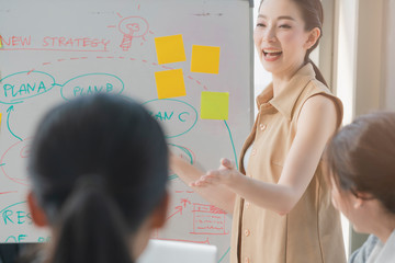 smart asian business female leader in a casual meeting with her teamwork colleagues at the modern desogn office presenting sales strategy plan and data or forecast for a project goal schedule