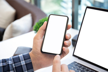 man holds phone over laptop with isolated screen on table