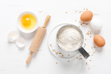 Fototapeta na wymiar Flour and eggs on white kitchen worktop, baking culinary background, copy space, overhead view