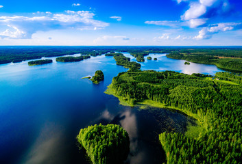 Aerial top view of blue lakes with islands and green forests in Finland.