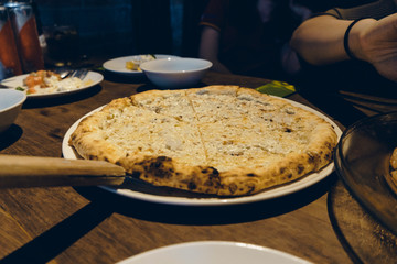 view of slice piece Salmon Sashimi pizza. Hand holding slice of pizza.
