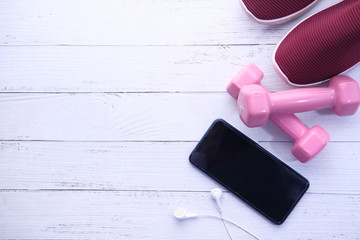 top view of smart phone, dumbbell, shoe on wooden background 