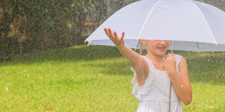 Little girl with umbrella playing in the rain.