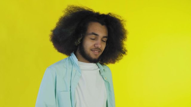 Young Afro-American man showing silence or bla bla gesture on yellow background. Concept of emotions
