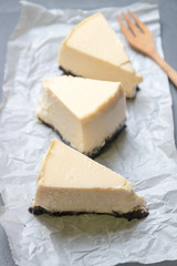 Creamy cheesecake with chocolate cookies slice on baking paper with black tray.