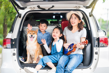 Happy asian children and Mother with shiba inu sitting and Sing Song in car.