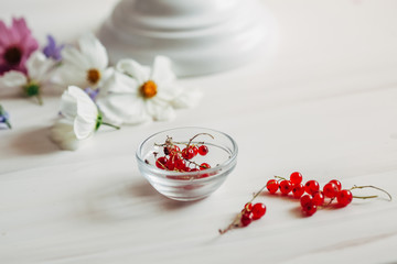 Red currant berries lie on a white table.