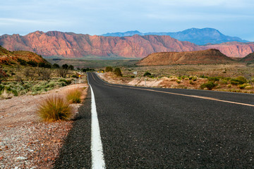 road in the desert of Utah shot low angle in the middle of the road with rocky red mountains as background  © manolo