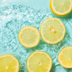 Slice of lemon underwater or in water with splashing and droplet top view flat lay on blue background