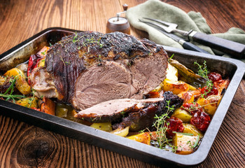 Traditional barbecue lamb roast sliced with tomatoes and fried potatoes as closeup in a metal tray
