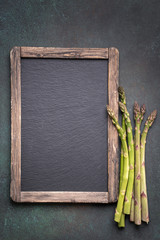 Rustic empty menu blackboard and asparagus on wooden background with copy space