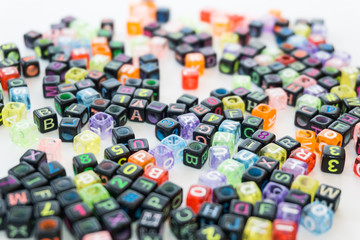 Colorful alphabets beads on white background, different colors with letters, concept image