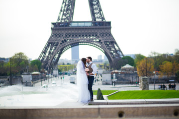 Bride and groom having a romantic moment on their wedding day in Paris, in front of the Eiffel tour