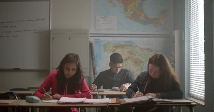 Young students in class studying hard and taking notes while in Geography class