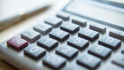 A calculator and pen on the desk. 
