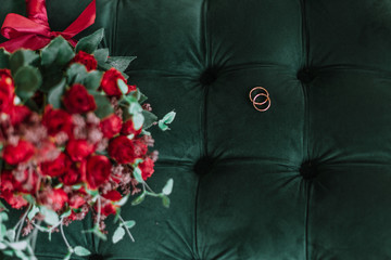 red rose wedding rings on green background