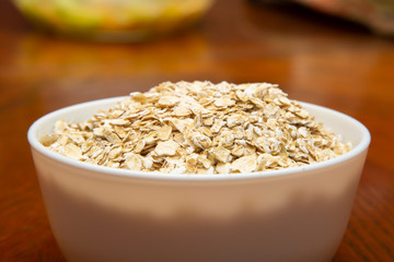 Oatmeal in a white Cup on a brown table.