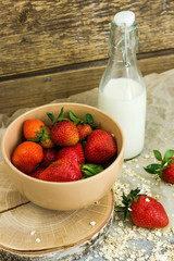 Breakfast strawberries with milk and oatmeal on a dark background