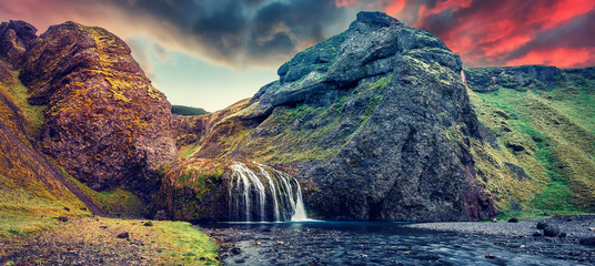 Fantastic Evening landscape with waterfall during sunset. Amazing Icelandic seascape. popular tourist attraction. Best famouse travel locations. Image of wild nature. Tipical Icelandic countryscape