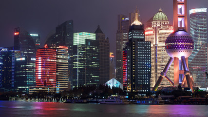 Night skyline of colorfully lighted Oriental Pearl TV Tower and other skyscrapers across Huangpu river