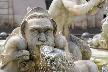 Fototapeta na wymiar A beautiful old stone fountain of a fish and abstract human head with running water from the mouth. Classical piece of art in the historical center of Rome, Italy