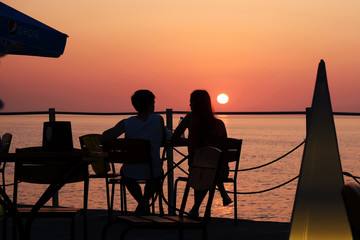 Fototapeta na wymiar Silhouette of couple enjoying romantic sunset on the pier