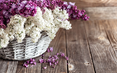 Fototapeta na wymiar Spring composition lilac flowers in a basket on a wooden background.