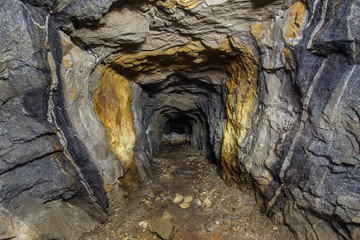 Underground abandoned mica ore mine tunnel with yellow dirt