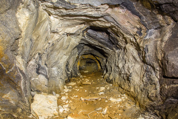 Underground abandoned mica ore mine tunnel with yellow dirt