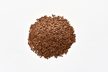 A pile of brown flax or flaxseed on a white background. View from above.