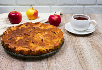 Homemade baked apple pie, in a plate, on a wooden table, ready to eat. View from above.