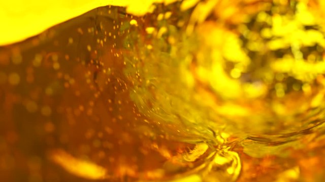 Beer with bubbles moves in a glass in slow motion