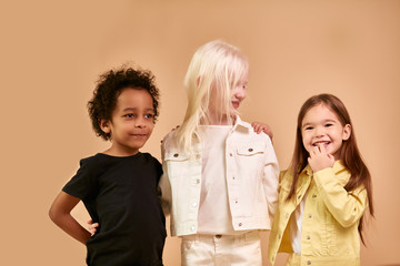 portrait of beautiful kids with natural unusual appearance. girl with albinism syndrome is friends with black african boy and american girl. children maintain tolerance and kindness to each other