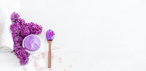 Background Spa composition for body care on a light wooden background with lilac flowers.